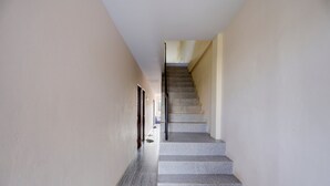 A narrow hallway with a staircase leading to a landing. - Hotel O Inara Homestay (Batam)