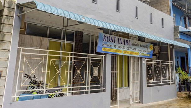 A building with a signboard advertising various facilities. - Hotel O Inara Homestay (Batam)
