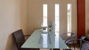 A dining area with a table, chairs, and a window with a view. - Hotel O Inara Homestay (Batam)