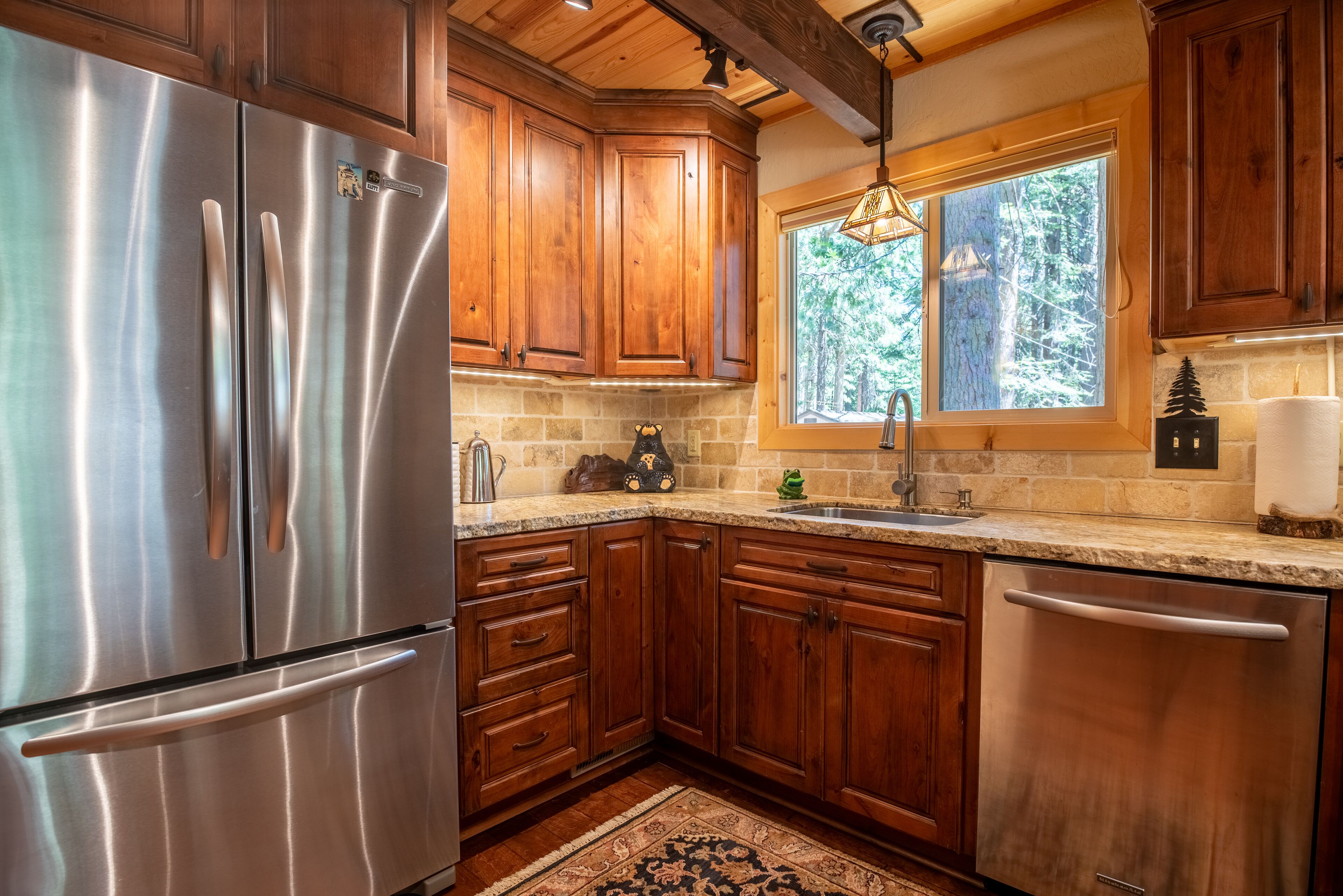 A kitchen with wooden cabinets, a stainless steel refrigerator, and a stone backsplash.