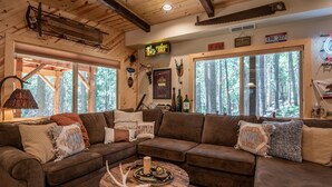 A cozy cabin interior with a large wooden ceiling, a brown leather couch, and a rustic coffee table. - Sukoon Retreat - Free Summer Pool Access! (Dorrington)
