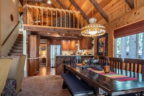 Cozy cabin with a dining table for four, a staircase, and a kitchen with wooden cabinets.