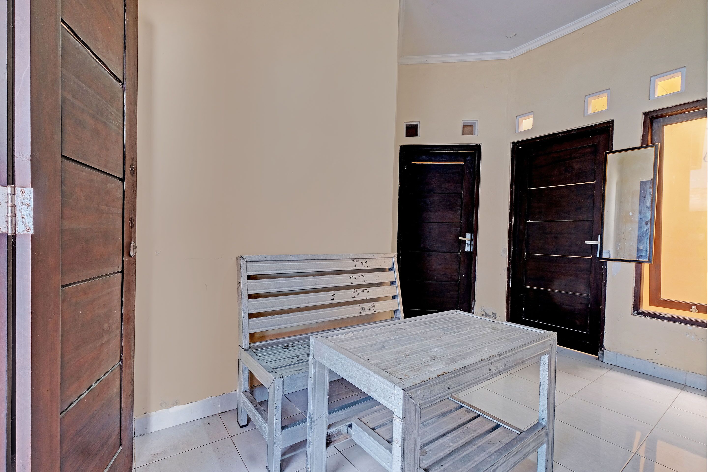 A room with a wooden bench, a small table, and two dark wooden doors.