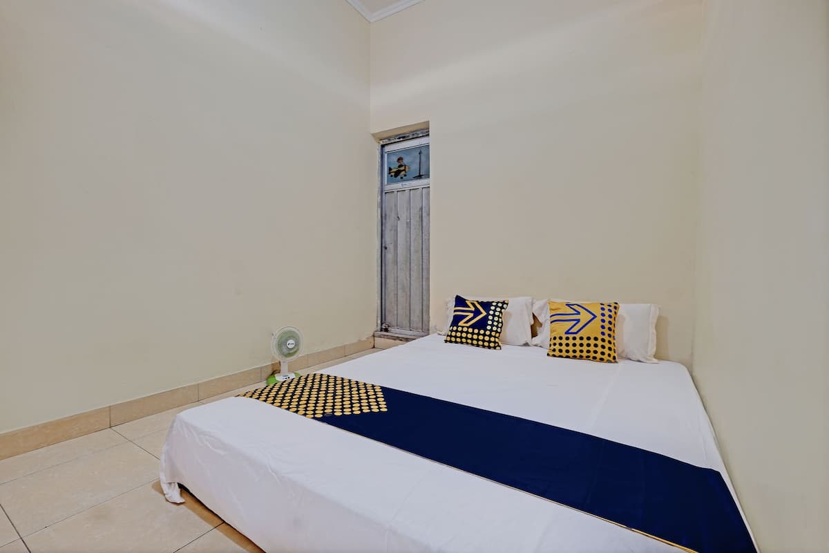 A bedroom with a bed, pillows, and a window.