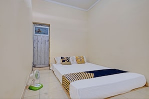 A single-bed room with a white bed, a green and white fan, and a door with a window. - SPOT ON 92934 Nusantara Syariah (Depok)
