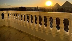 Ein Balkon mit Blick auf den Sonnenuntergang und Pyramiden im Hintergrund.