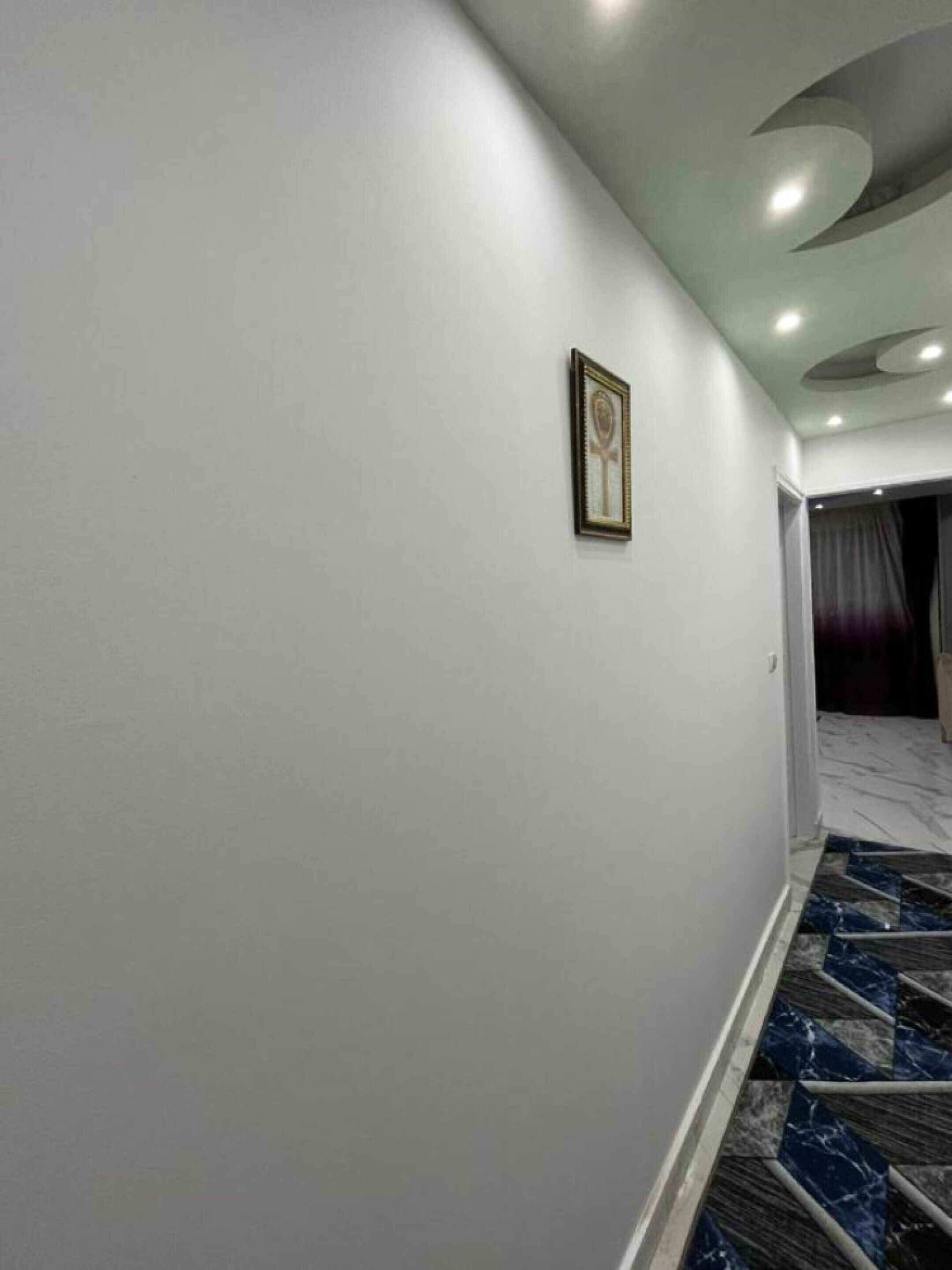 Un pasillo con piso de mármol y un cuadro en la pared.
