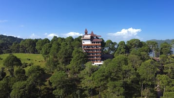 A multi-story building with a unique architectural design, surrounded by dense forest.
