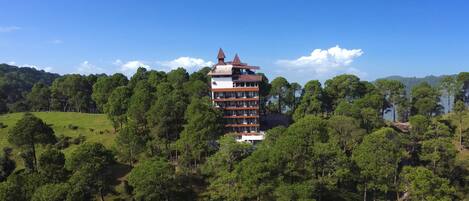 Um edifício com vários andares e design arquitetônico singular, cercado por uma floresta densa.