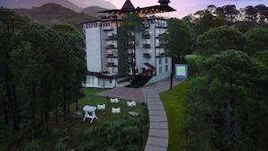 A multi-story hotel with a unique architectural design, featuring a central courtyard with outdoor seating and a pathway leading to the entrance. - Lemon Tree Hotel Mcleodganj (Dharamshala)