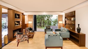 A spacious living room with a fireplace, comfortable seating, and a bookshelf. - Lemon Tree Hotel Mcleodganj (Dharamshala)