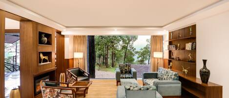 A spacious living room with a fireplace, comfortable seating, and a bookshelf.