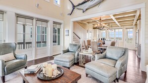 A spacious living area with leather armchairs, a wooden coffee table with candles, and a large fish mounted on the wall. - Stunning Lakeside Home near Keira’s Pool & More Cinnamon Shore Amenities. (Port Aransas)