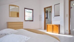 Una camera da letto con un letto, una cassettiera, uno specchio e una finestra.