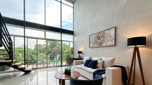 A spacious living room with a large window, a sofa, a coffee table, and a floor lamp.