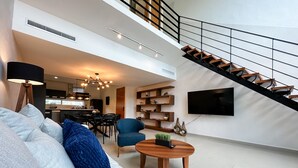 A modern living room with a sofa, coffee table, and a staircase leading to an upper level.