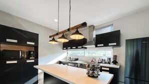A modern kitchen with a central island, black cabinetry, and pendant lighting.