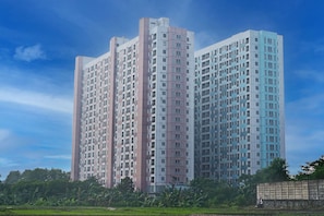 A high-rise residential building with multiple floors, large windows, and a uniform facade. - Collection O 92959 Apartement Sentraland Karawang By AT Room (Karawang)