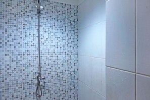 A shower area with a polka dot tile pattern and a handheld showerhead. - Collection O 92959 Apartement Sentraland Karawang By AT Room (Karawang)