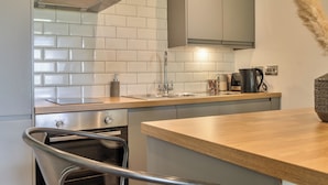 A modern kitchen with white tiles, stainless steel appliances, and a wooden countertop. - Modern Peaceful Open Plan 1-bed Apartment Rutland (Oakham)