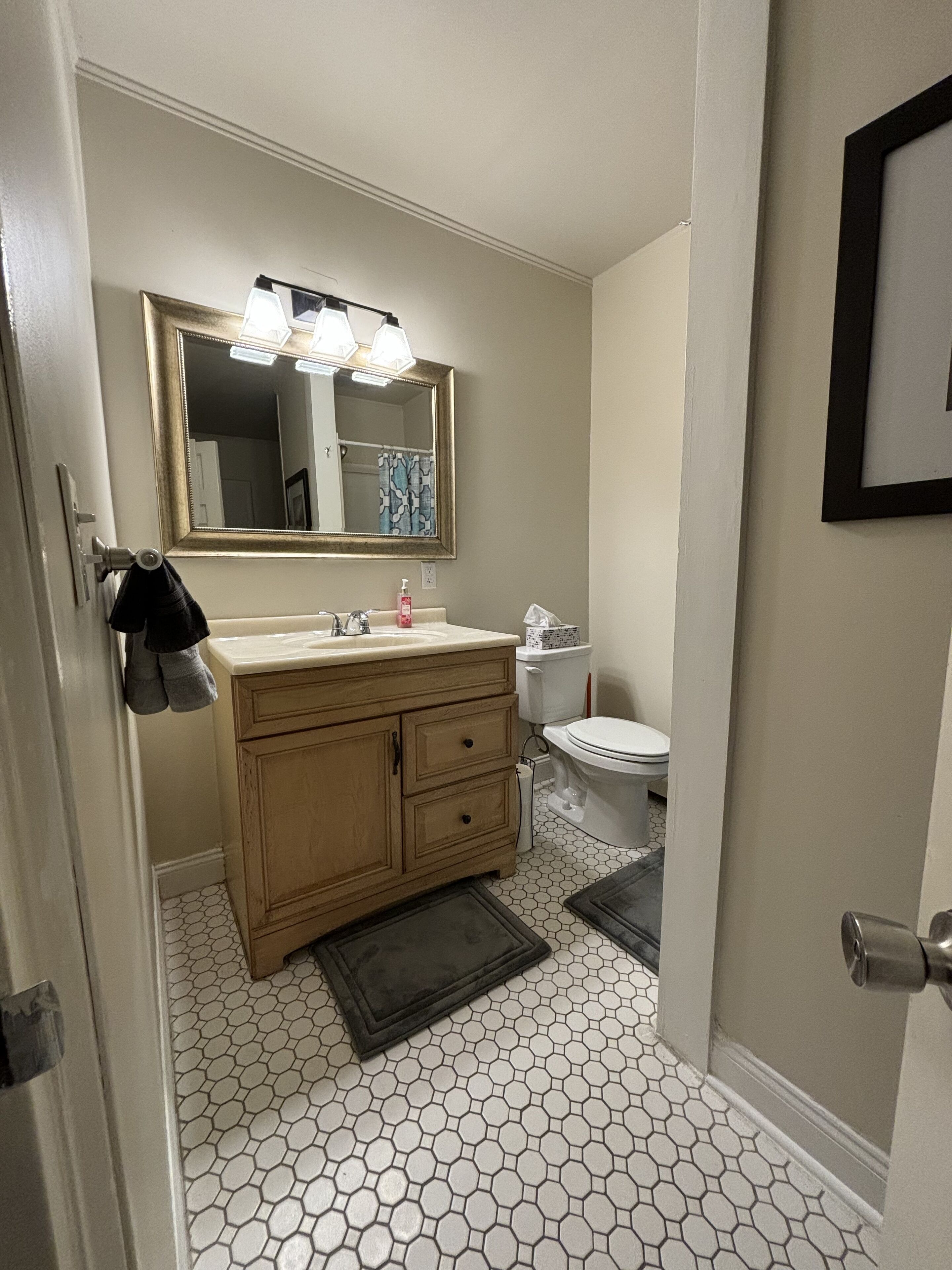 A bathroom with a hexagonal tile floor, a sink with a mirror above it, and a toilet.