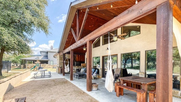 Un espacio al aire libre techado con bancos de madera, mesas de picnic y una chimenea de piedra.