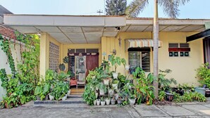 A building with a covered entrance, potted plants, and a small shop. - OYO 92998 Wiludjeng Guesthouse (Sragen)