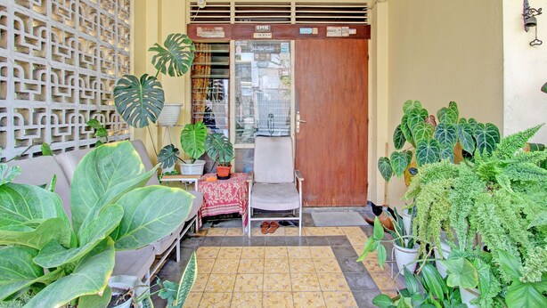 A small, enclosed porch area with a wooden door, a tiled floor, and various potted plants. - OYO 92998 Wiludjeng Guesthouse (Sragen)