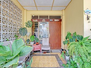 A small, enclosed porch area with a wooden door, a tiled floor, and various potted plants. - OYO 92998 Wiludjeng Guesthouse (Sragen)