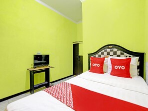 A hotel room with a bed, a TV on a small table, and a wardrobe.
