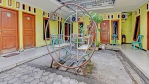 A courtyard with a metal swing, potted plants, and a tiled floor. - OYO 92998 Wiludjeng Guesthouse (Sragen)