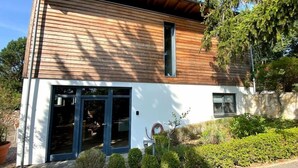 A modern two-story house with a wooden facade and a large glass door entrance.