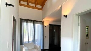 A modern interior with a white sofa, dark flooring, and wooden ceiling beams.