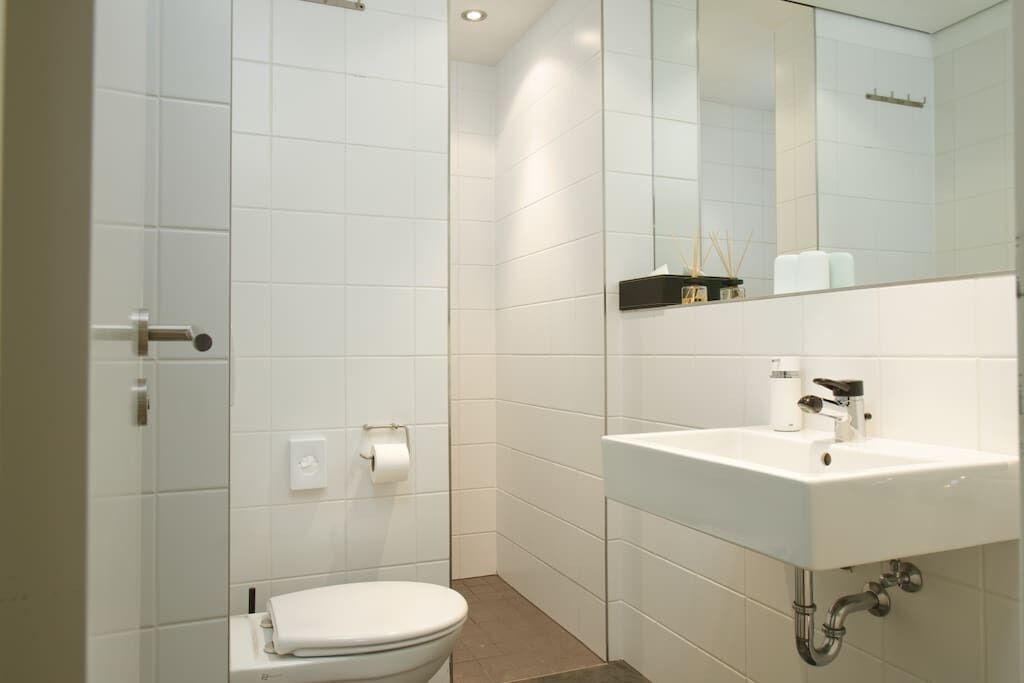 A modern bathroom with a toilet, sink, and mirror.