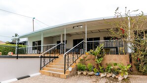 A modern house with a covered porch, a staircase, and potted plants. - Stunning 3-bed House in Kigali (Kigali)