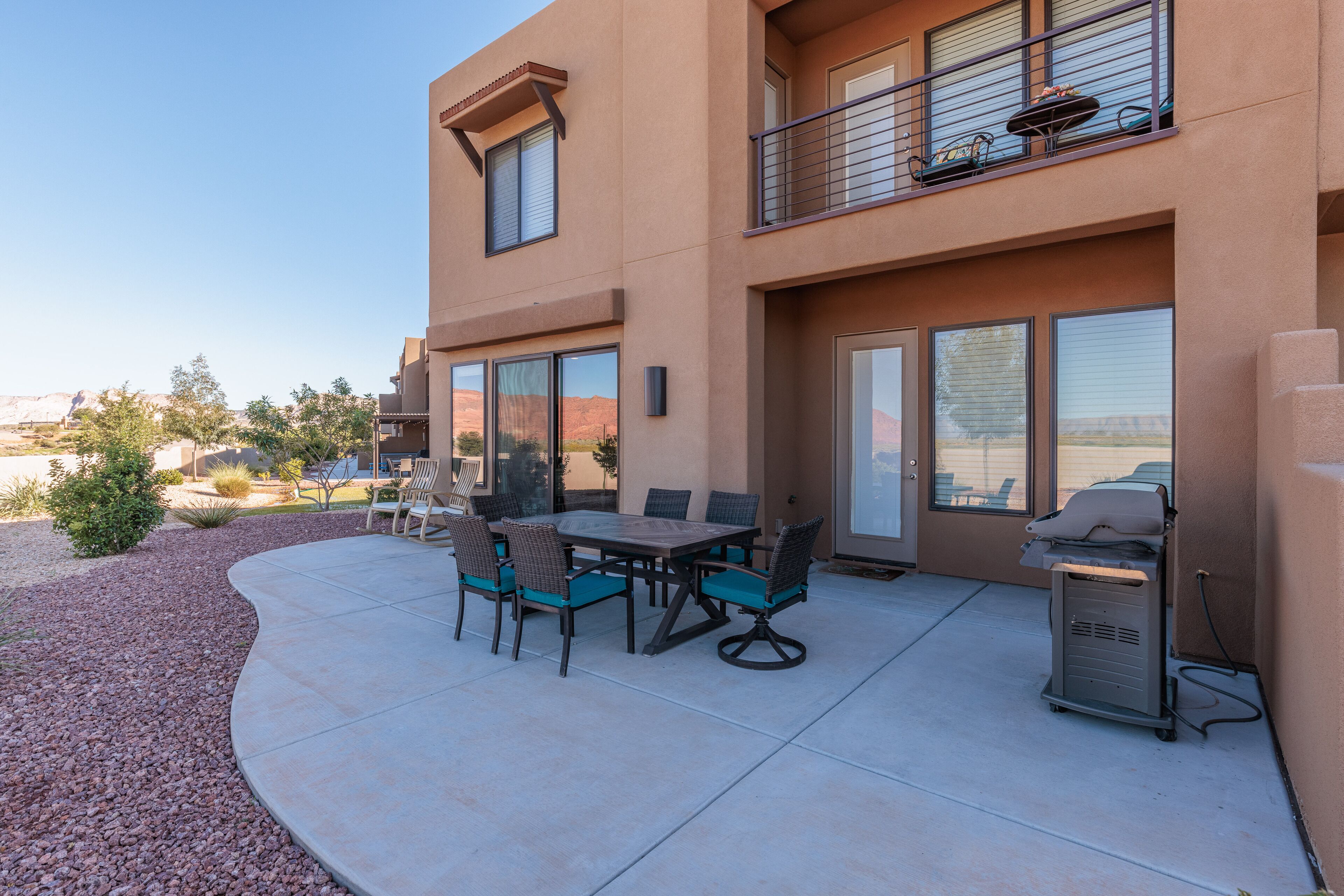 A patio with a table and chairs, a grill, and a view of the mountains.