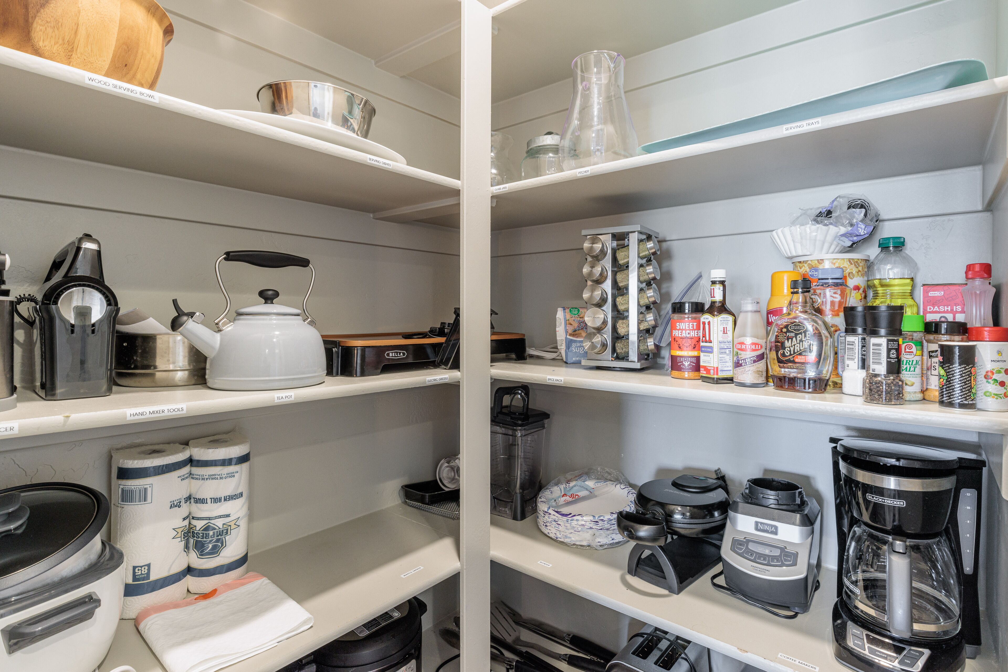 Una cocina con estantes llenos de utensilios, electrodomésticos y alimentos.