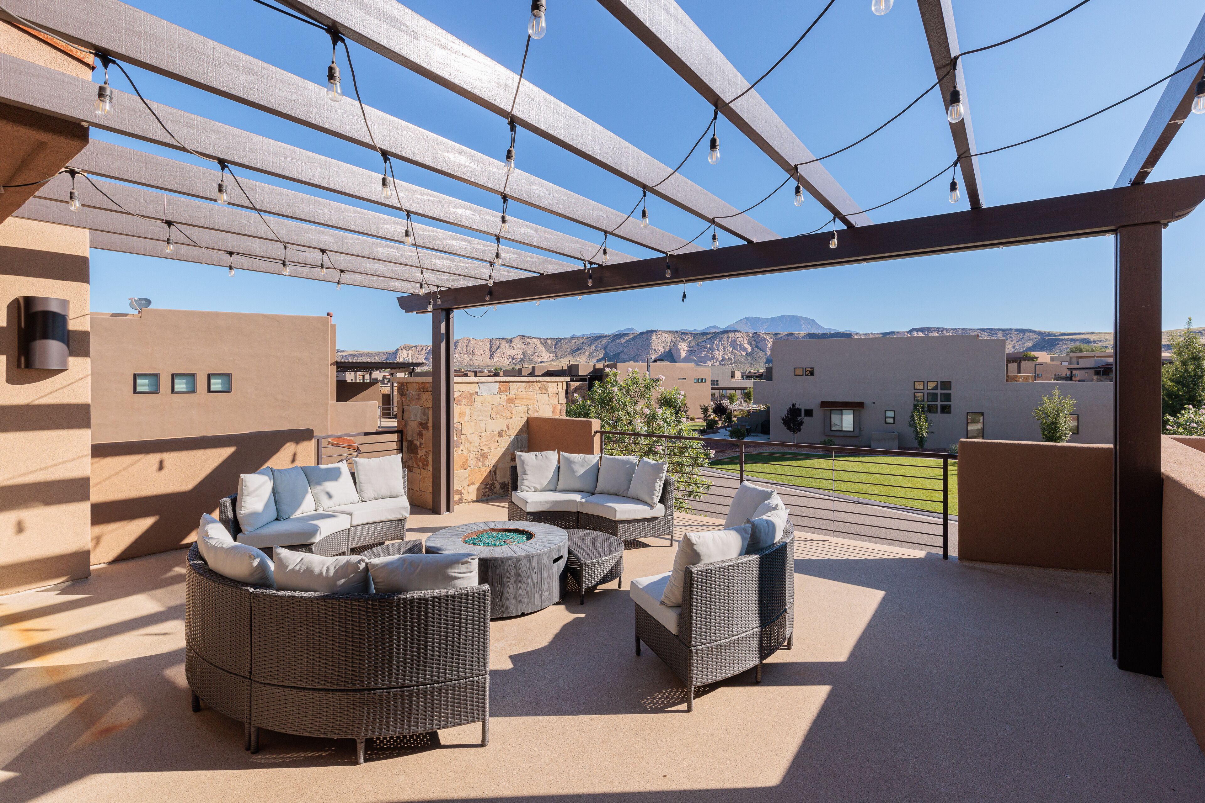 Une terrasse extérieure aménagée avec des meubles en osier, un foyer et une vue sur les montagnes.