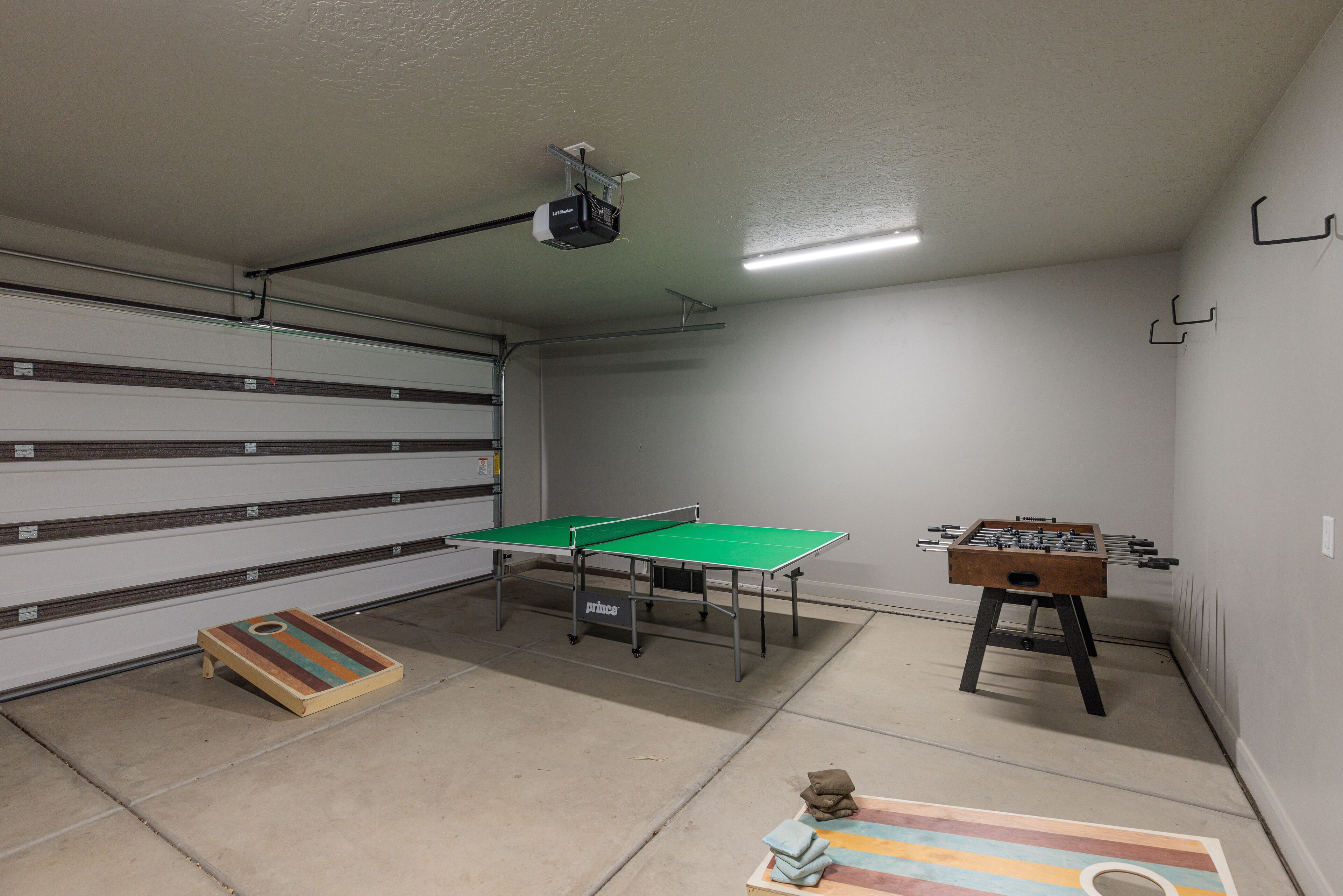 A room with a ping pong table, foosball table, and a dartboard.