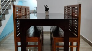 Un coin repas avec une table à plateau en verre et des chaises en bois à dossier ajouré.