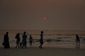 A beach scene with people walking along the shore.