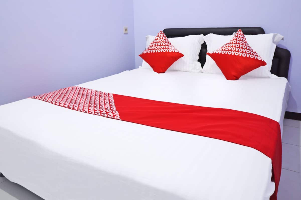 A bed with white bedding and red accents, including pillows and a throw blanket.