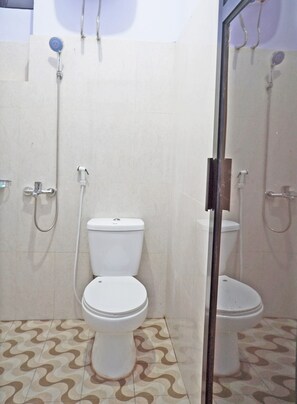 A bathroom with two toilets, a shower, and a tiled floor.