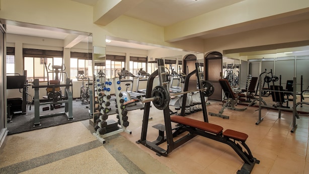 Une salle de sport équipée de divers appareils d’entraînement, notamment des machines de musculation, des tapis de course et des poids libres.