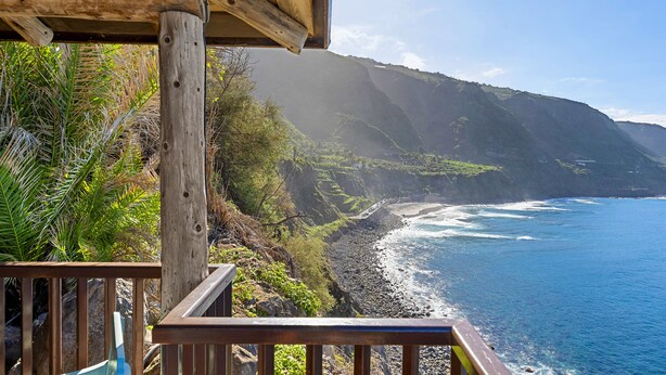A wooden deck overlooking a coastal cliff with a view of the ocean.
