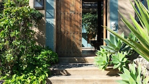 A wooden door with metal studs, a lantern, and steps leading to a building.