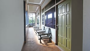 A hallway with a row of benches, a green door, and a window with a view of greenery. - SPOT ON 92973 Madani Syariah Guesthouse (Praya)