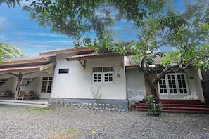 A building with a tiled roof, a small porch with wooden chairs, and a staircase leading to the entrance. - SPOT ON 92973 Madani Syariah Guesthouse (Praya)
