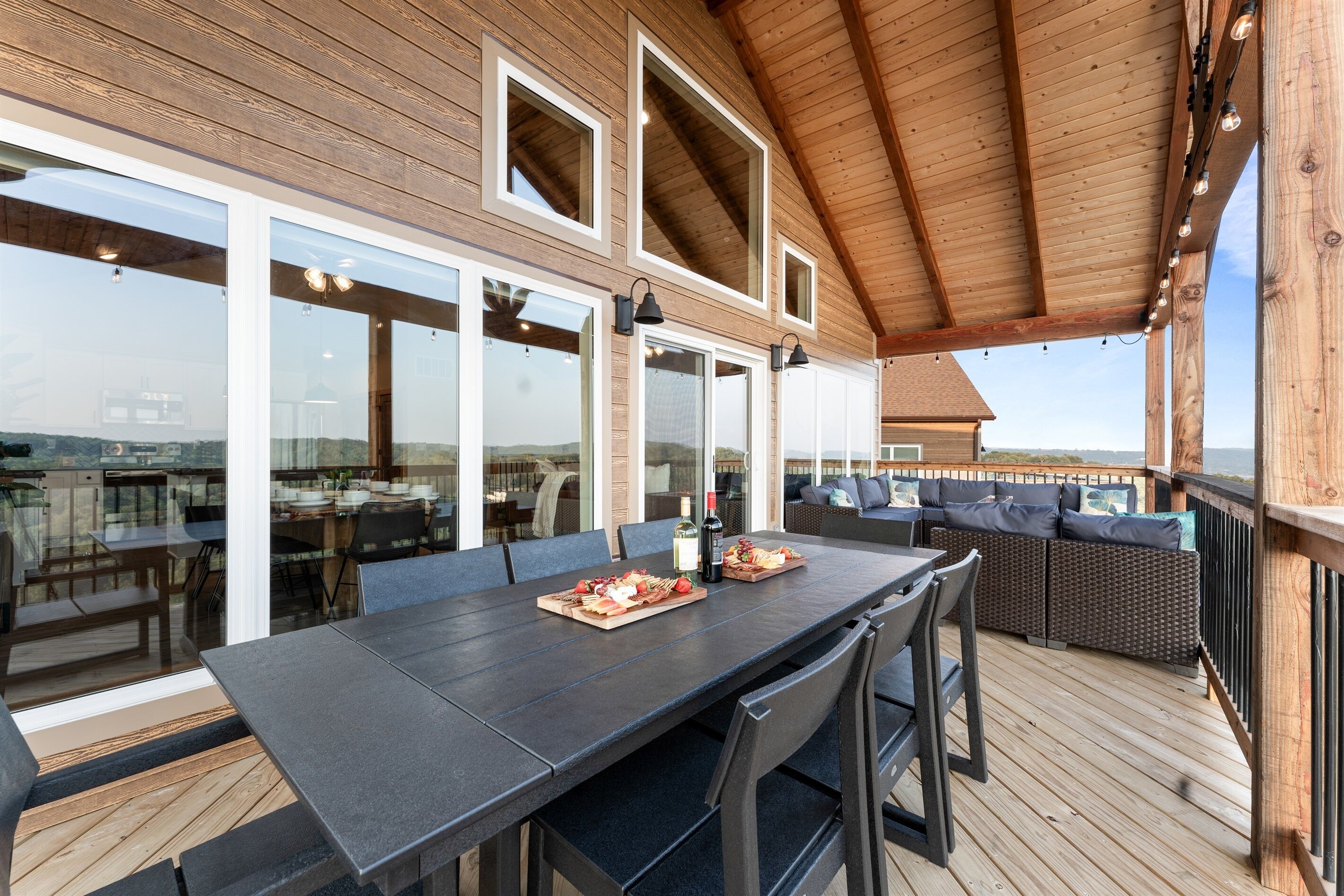 An outdoor dining area with a long table, chairs, and a wooden deck.