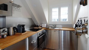 Una cocina moderna con electrodomésticos de acero inoxidable, encimera de madera y ventana que proporciona luz natural.